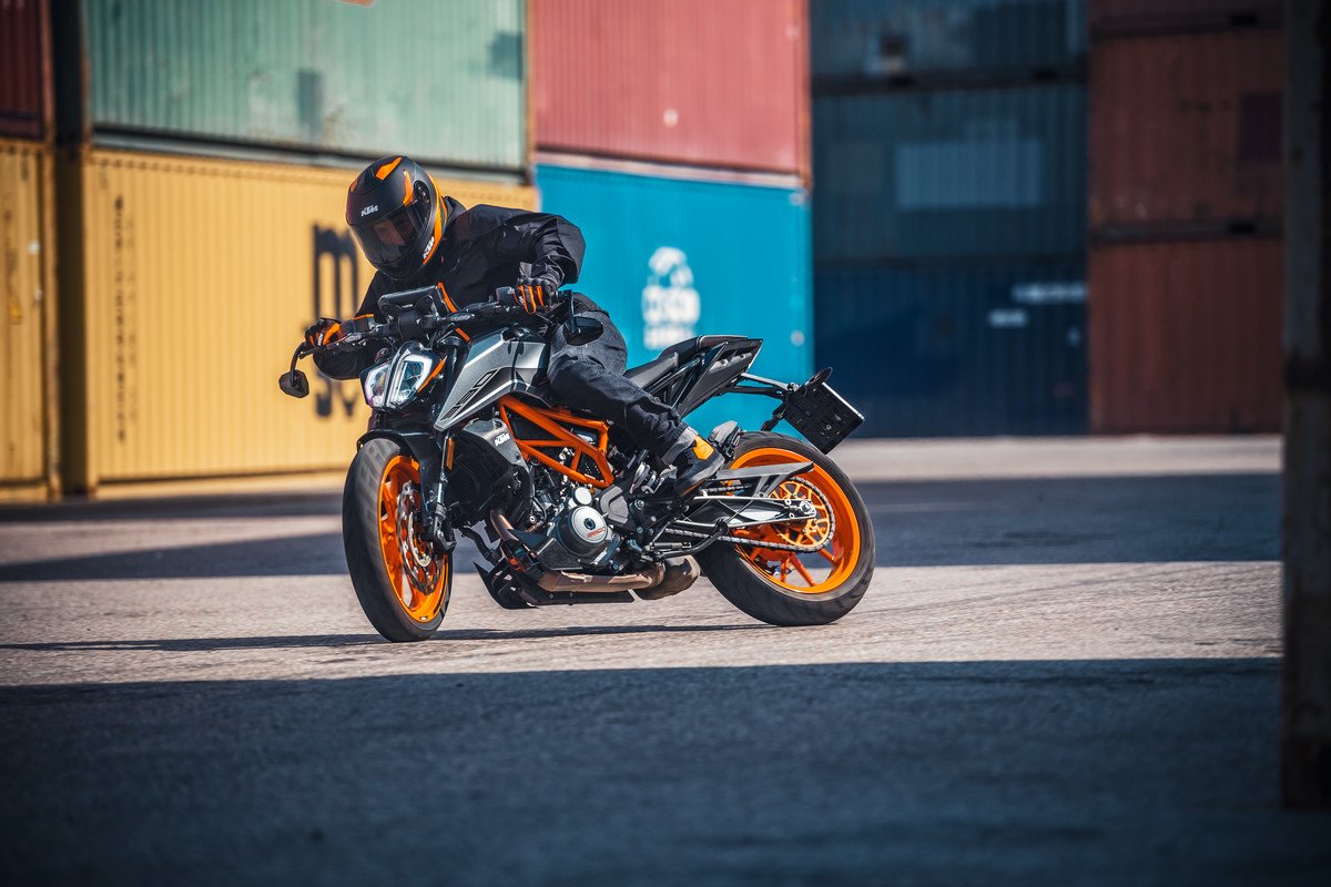 Rider turning on KTM 390 Duke near shipping containers