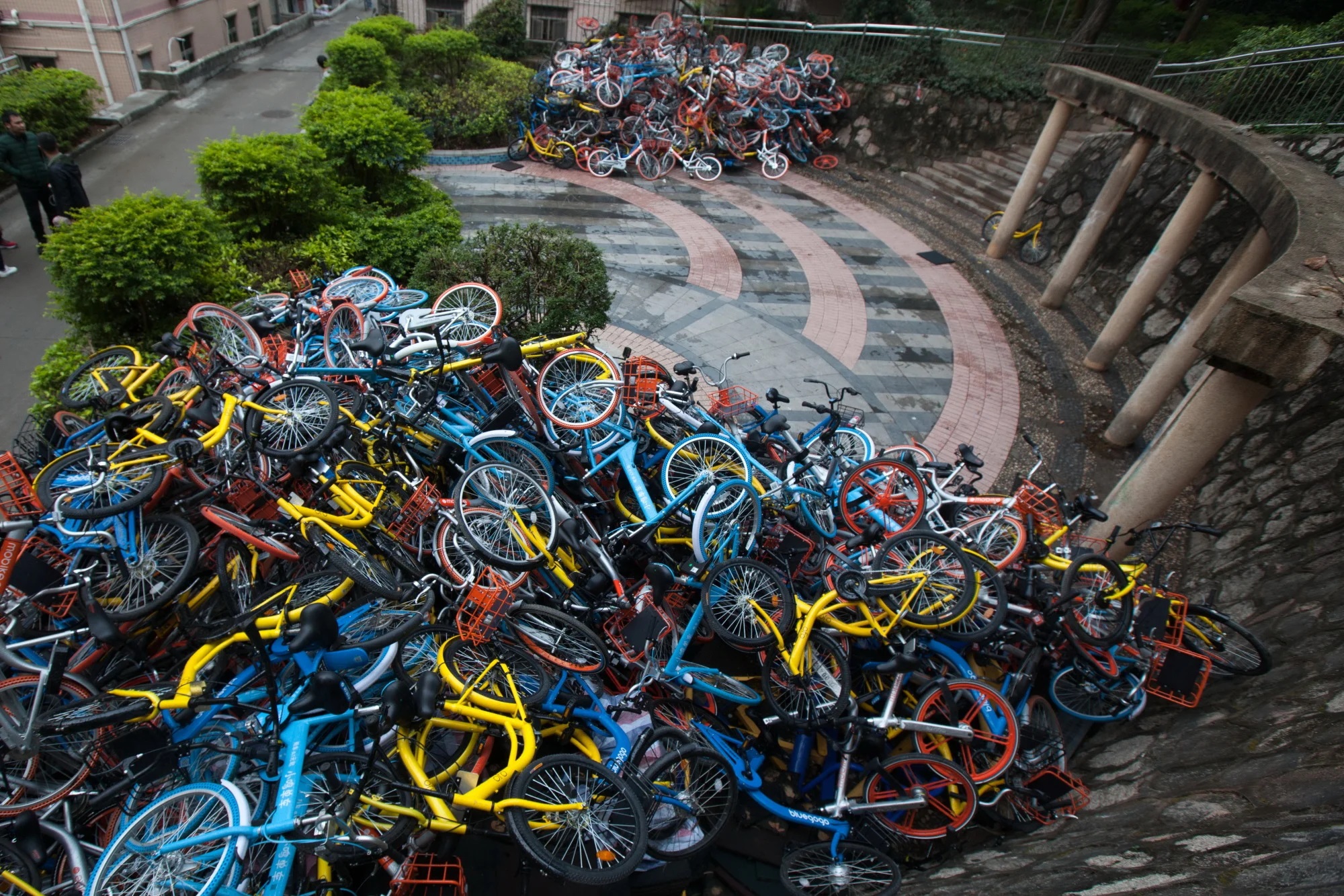 Two large piles of discarded and broken bicycles in urban city