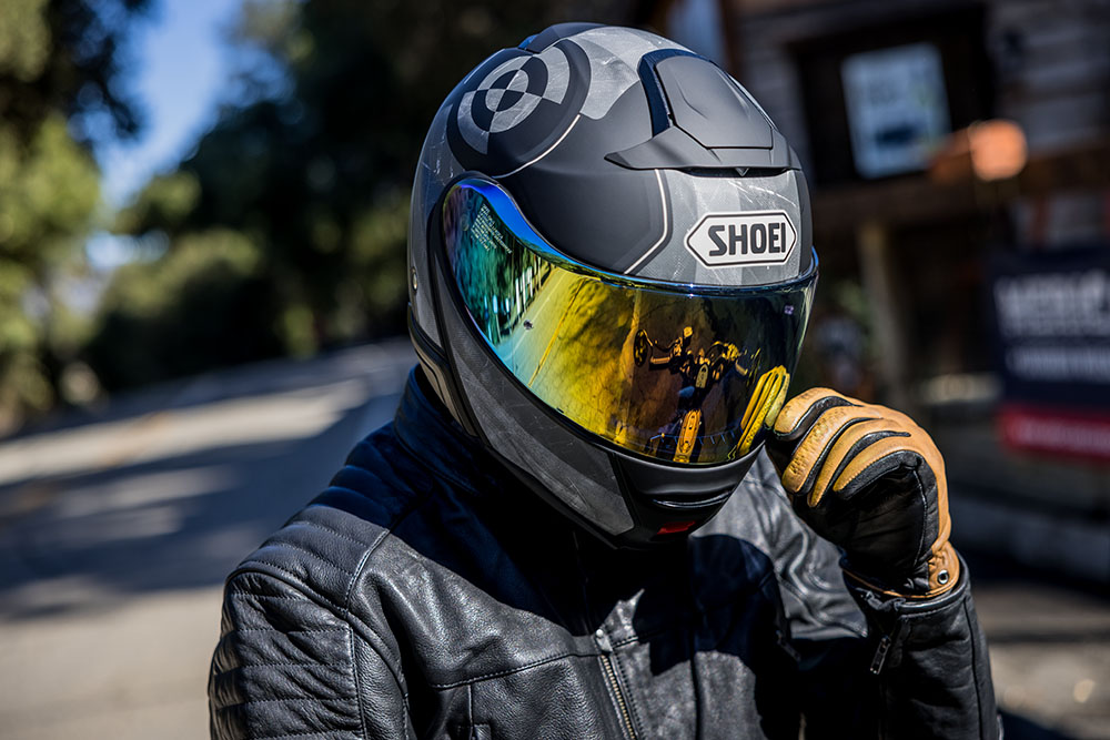 A close up image of a rider wearing a Shoei helmet with a tinted visor.