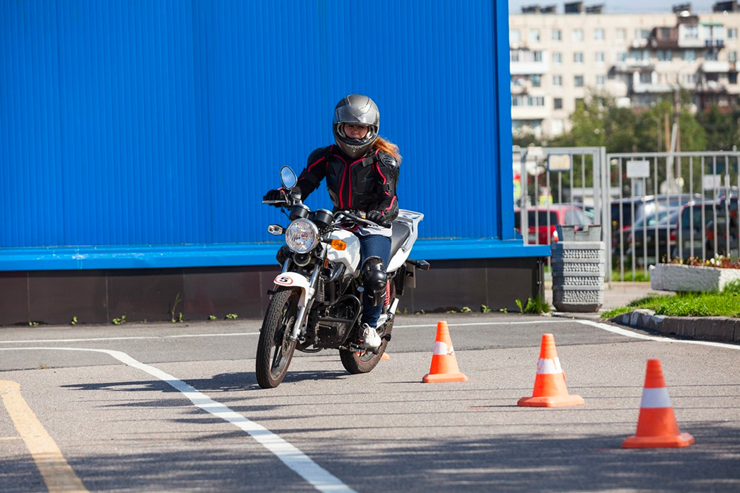 Motorcyclist turning around pylons in car park area