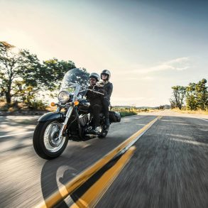 Couple riding on Kawasaki Vulcan 900 Classic LT down sunny rural road
