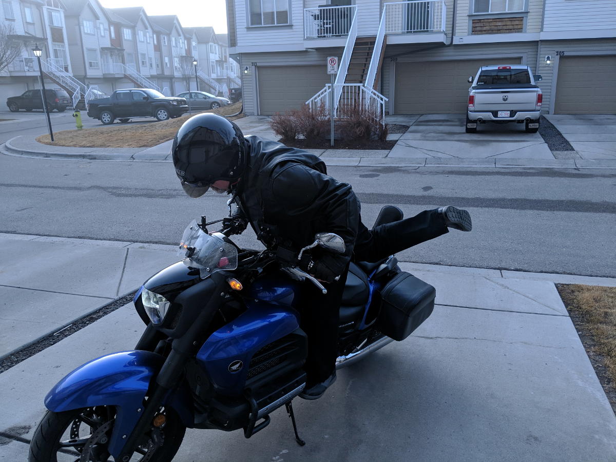 motorcyclist mounting motorcycle using peg as footing front view