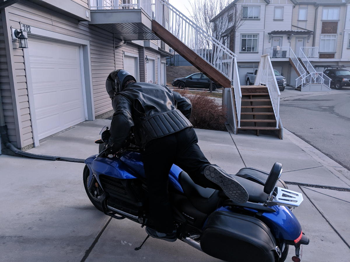 motorcyclist mounting motorcycle using peg as footing front view