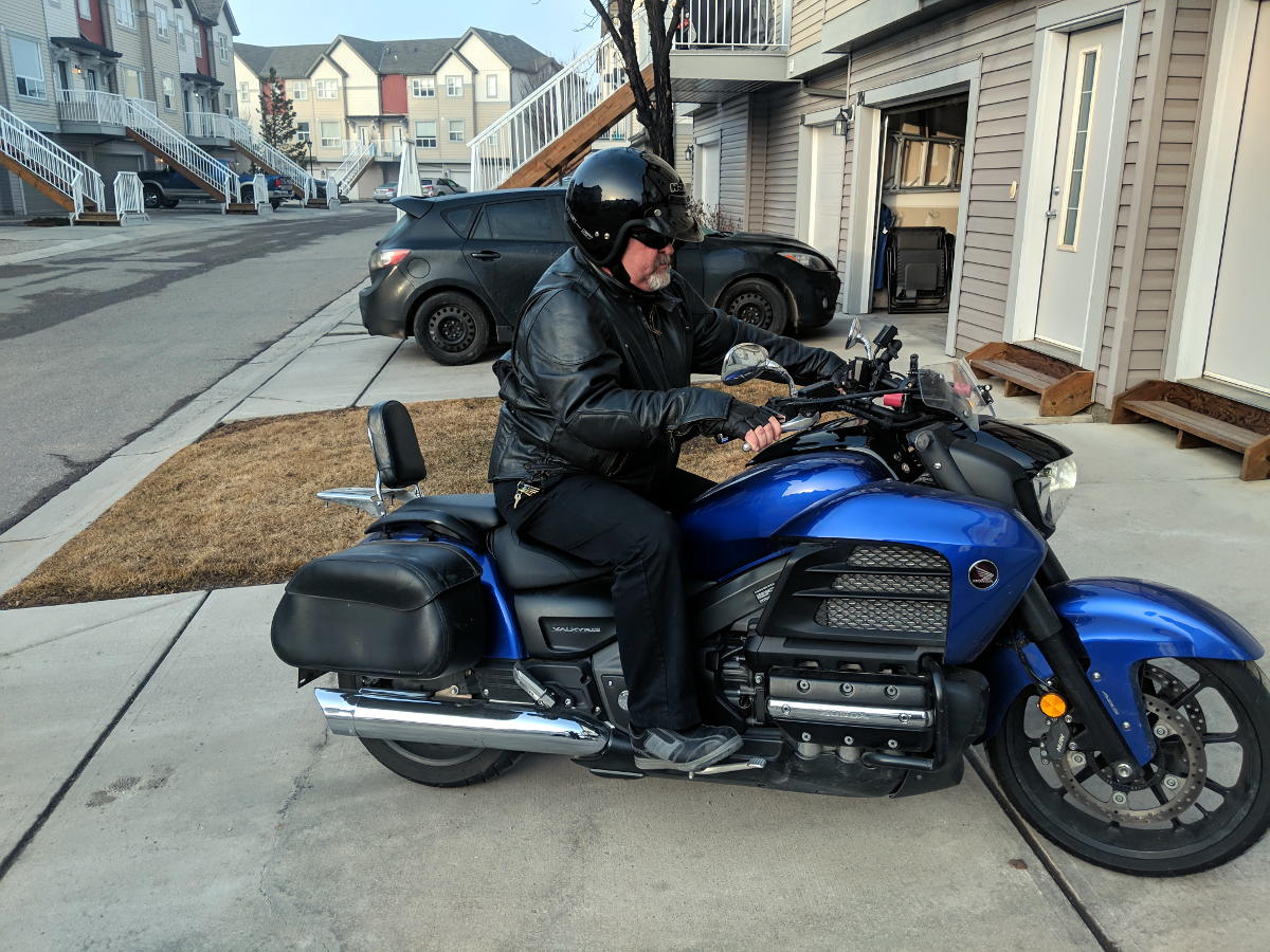 Motorcyclist mounting motorcycle now with right foot on peg