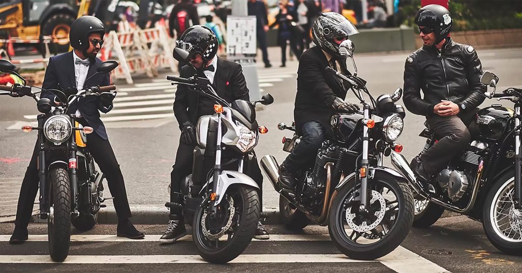 four motorcyclists parked next to each other chat casually at a group ride