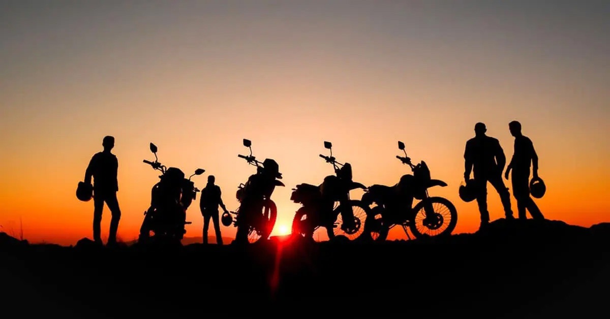 a group of off road motorcyclists stop to watch the sun set