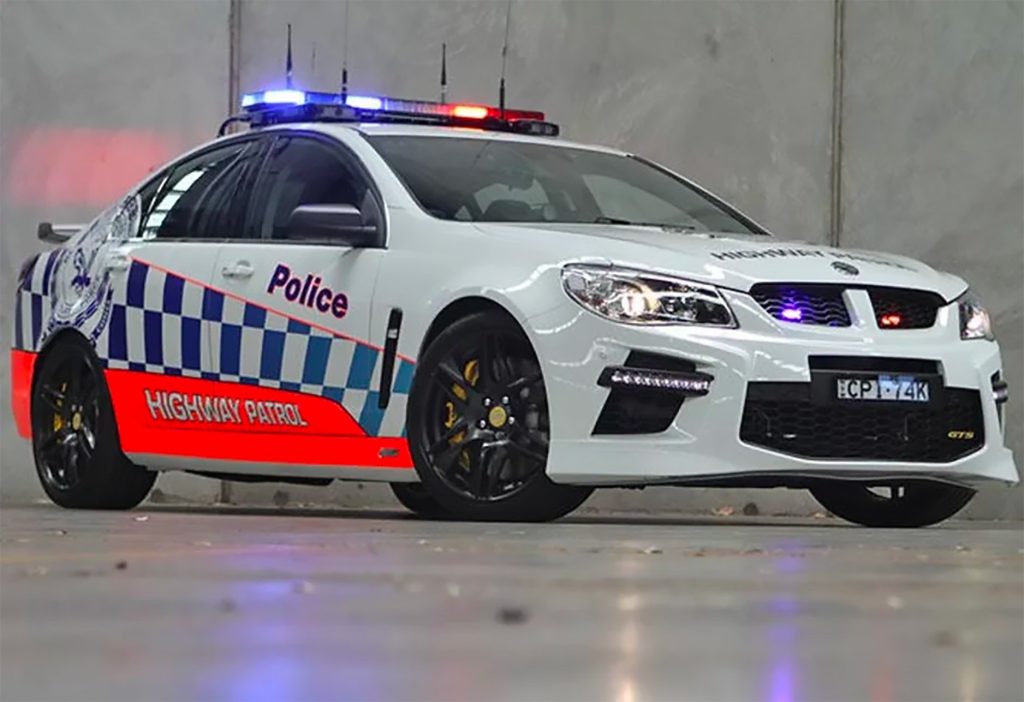An Australian V8 police car with its lights on in a garage