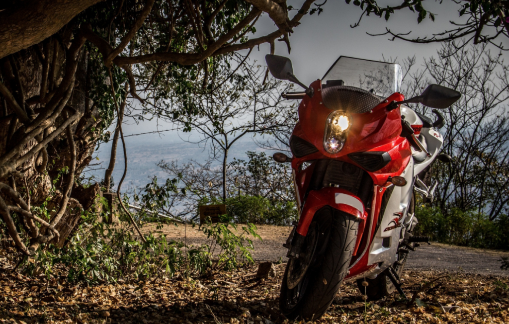 Hyosung GT250R parked near trees with ocean in background